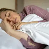 Kvinna sover oroligt, kanske bara sova 5 timmar per natt. Hon ligger i sängen med en näsgrimma.