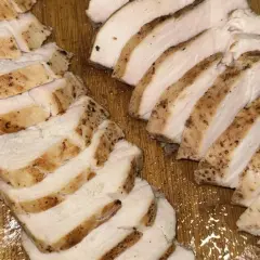 Skivat, saftigt kycklingbröst med kryddor på en träskärbräda. Perfekt för en snabb måltid, inte rå kyckling.