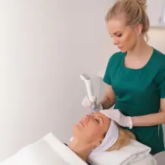 En hudterapeut använder Dermapen4 för att behandla en kvinnas ansikte.