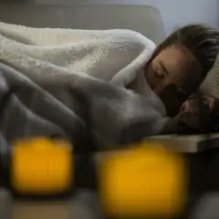 En kvinna sover på en soffa, insvept i filtar. Hon verkar sjuk. Hur vet man om man har lunginflammation?