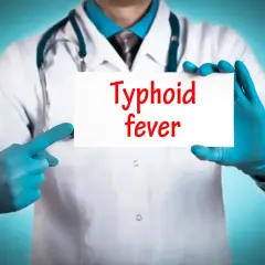 Läkare med blå handskar håller upp en skylt med texten "Typhoid fever". Snabb tyfus behandling är avgörande.
