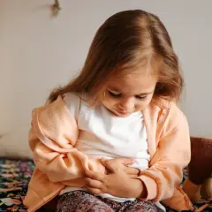 Liten flicka med magknip, håller sig om magen. Tips för att lindra magont hos barn.