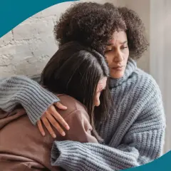 En kvinna tröstar sin deprimerade partner. Hon håller om henne med en varm kram, en gest av stöd och kärlek.