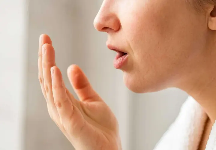 När en person känner efter dålig andedräkt, som kan bero på svamp i munnen (candidiasis cancer).