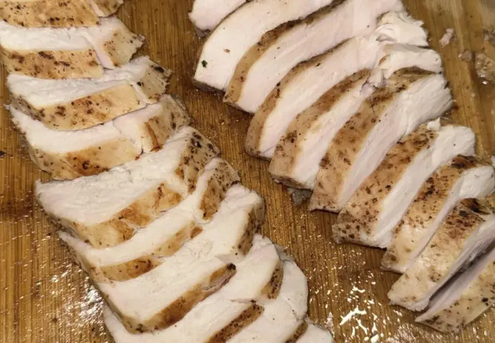 Skivat, saftigt kycklingbröst med kryddor på en träskärbräda. Perfekt för en snabb måltid, inte rå kyckling.