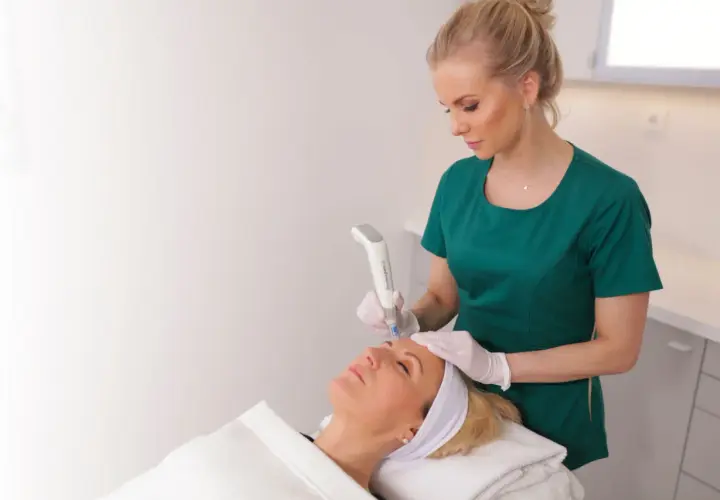 En hudterapeut använder Dermapen4 för att behandla en kvinnas ansikte.