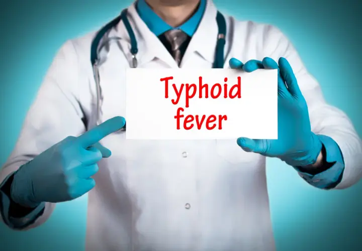 Läkare med blå handskar håller upp en skylt med texten "Typhoid fever". Snabb tyfus behandling är avgörande.