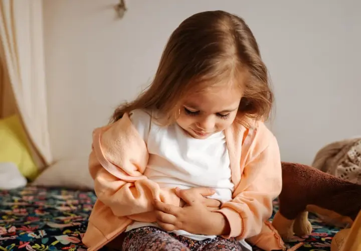 Liten flicka med magknip, håller sig om magen. Tips för att lindra magont hos barn.