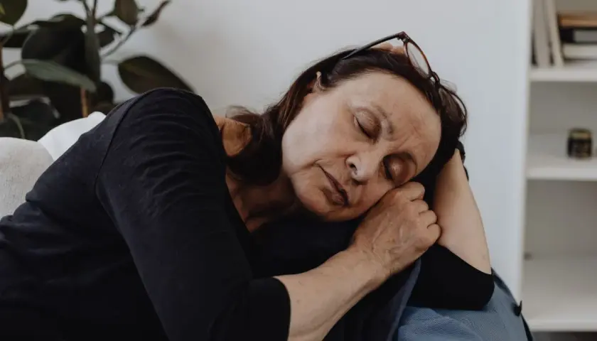 En kvinna vilar på en soffa, ögonen slutna, en bild av djup fatigue svenska.