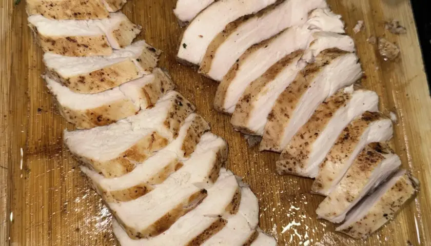 Skivat, saftigt kycklingbröst med kryddor på en träskärbräda. Perfekt för en snabb måltid, inte rå kyckling.