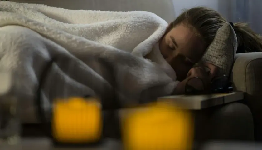 En kvinna sover på en soffa, insvept i filtar. Hon verkar sjuk. Hur vet man om man har lunginflammation?