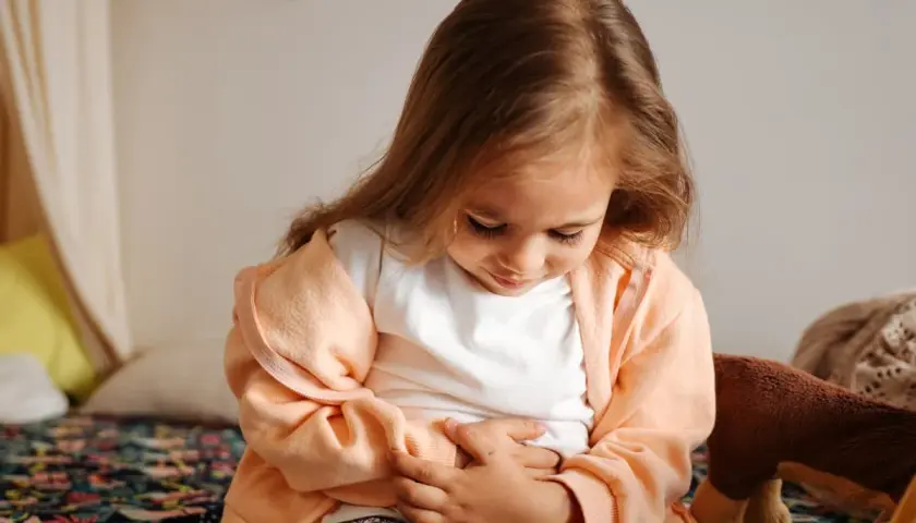Liten flicka med magknip, håller sig om magen. Tips för att lindra magont hos barn.