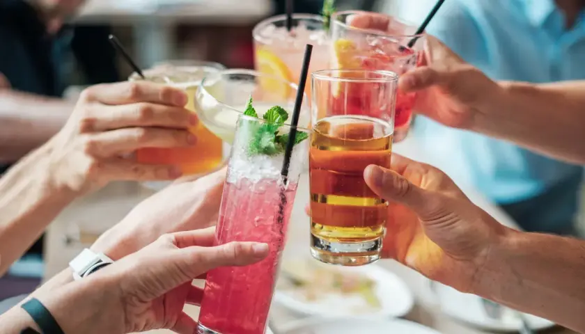 Händer som skålar med färgglada drinkar. En känsla av gemenskap, men för vissa kan alkoholen leda till ångest.