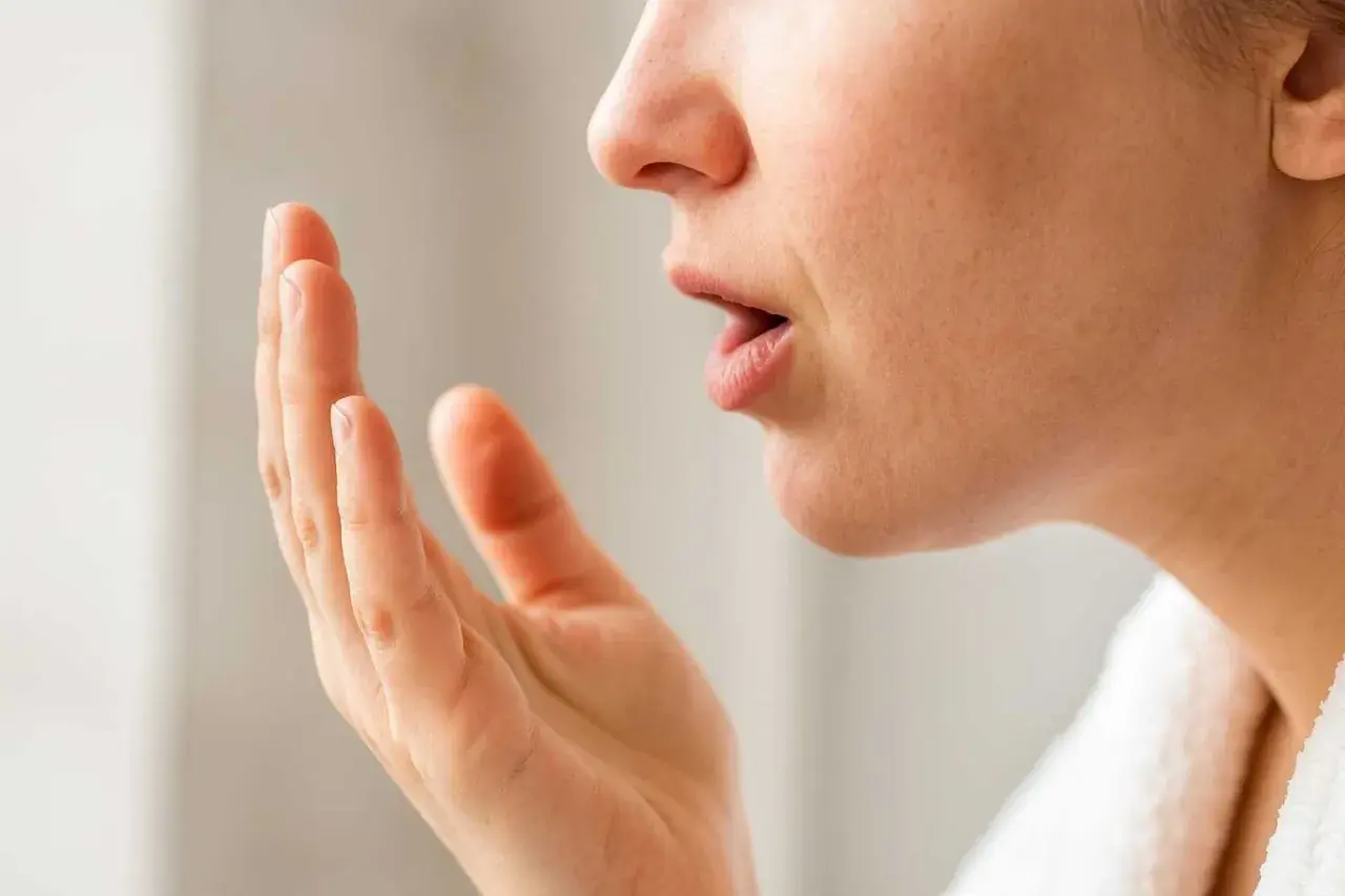 När en person känner efter dålig andedräkt, som kan bero på svamp i munnen (candidiasis cancer).