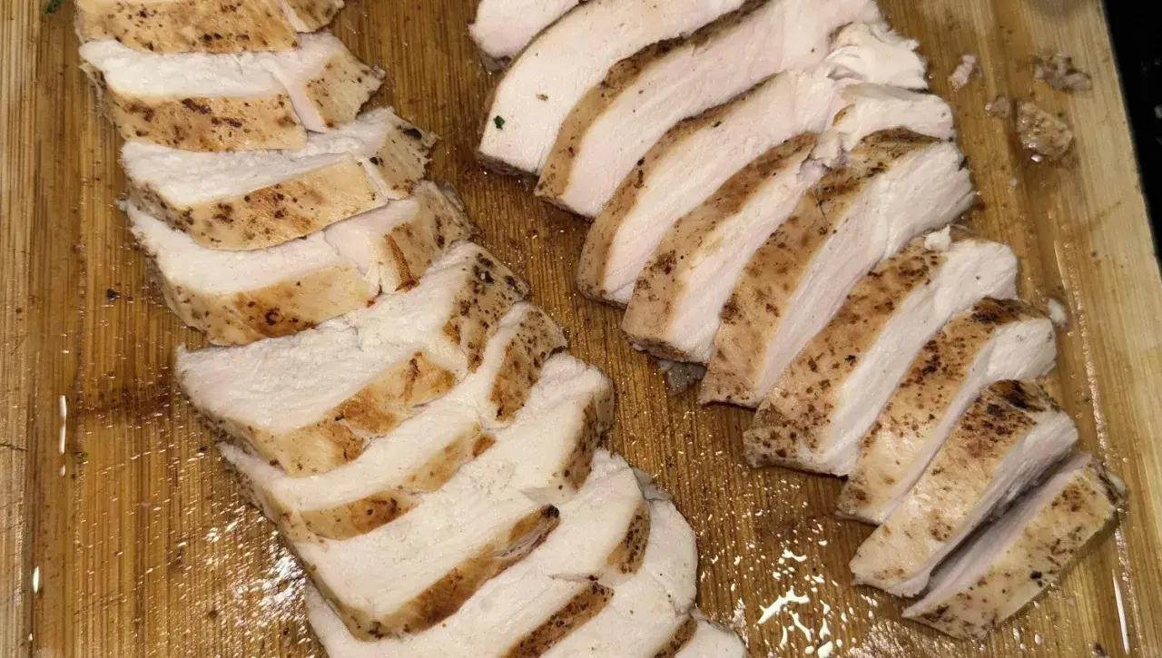 Skivat, saftigt kycklingbröst med kryddor på en träskärbräda. Perfekt för en snabb måltid, inte rå kyckling.