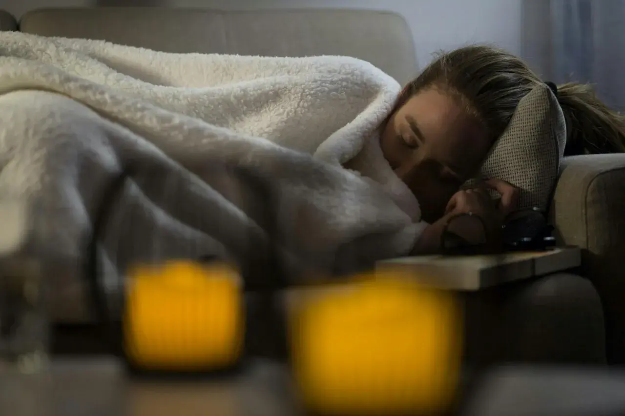 En kvinna sover på en soffa, insvept i filtar. Hon verkar sjuk. Hur vet man om man har lunginflammation?