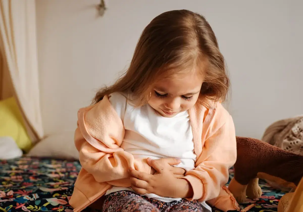 Liten flicka med magknip, håller sig om magen. Tips för att lindra magont hos barn.