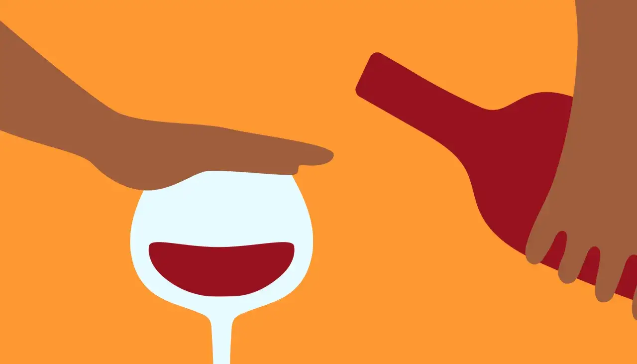 En hand stoppar ett vinglas med rött vin, medan en flaska hälls. Symboliserar ångest av alkohol och kampen för att sluta.
